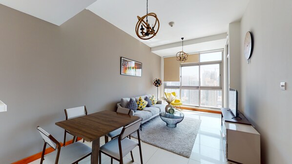 A modern living room with a dining area, large windows, and a view of the cityscape.