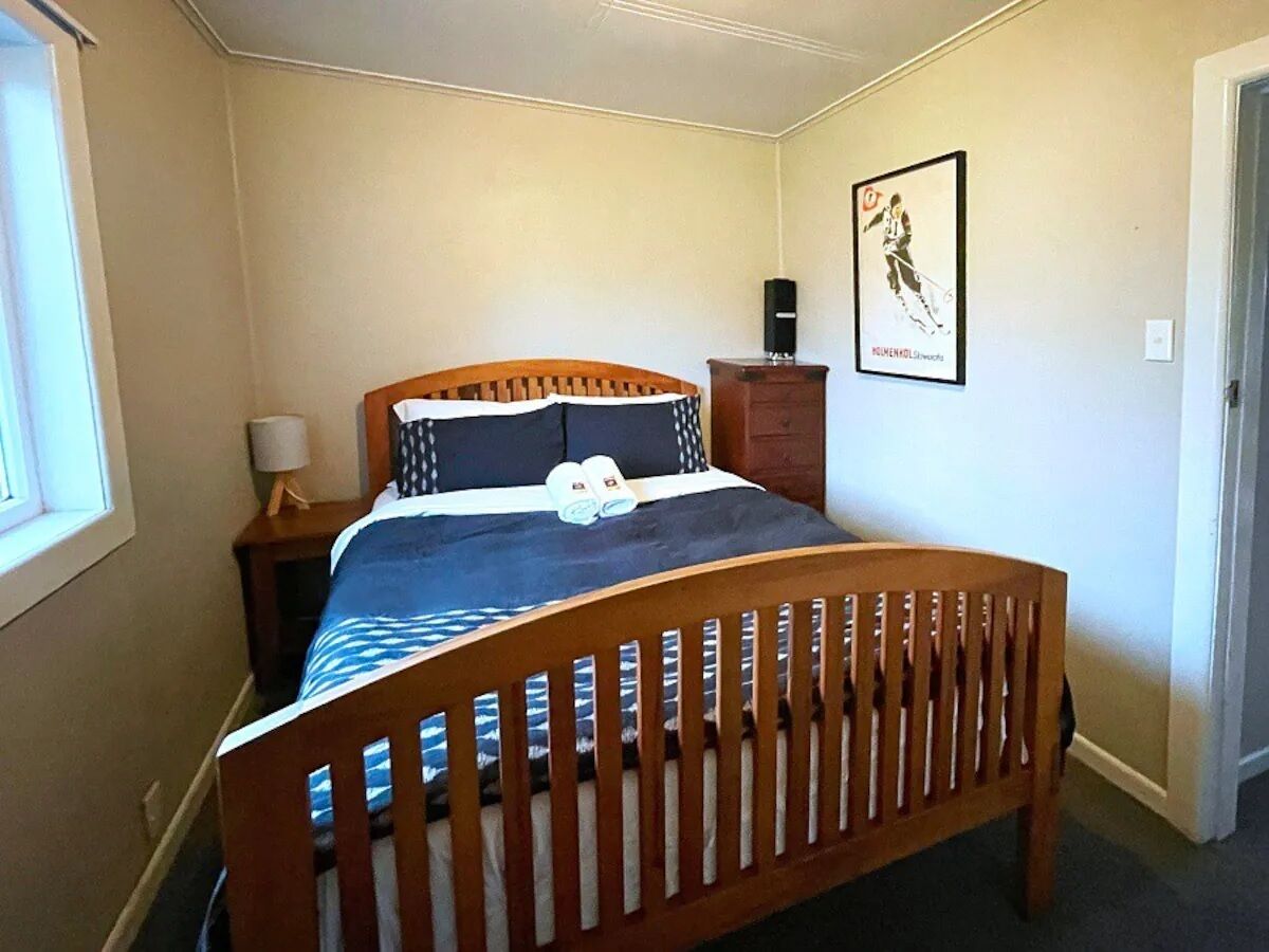 Une chambre à coucher avec un lit en bois, une table de chevet, une lampe et une affiche accrochée au mur.