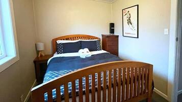 Une chambre à coucher avec un lit en bois, une table de chevet, une lampe et une affiche accrochée au mur.