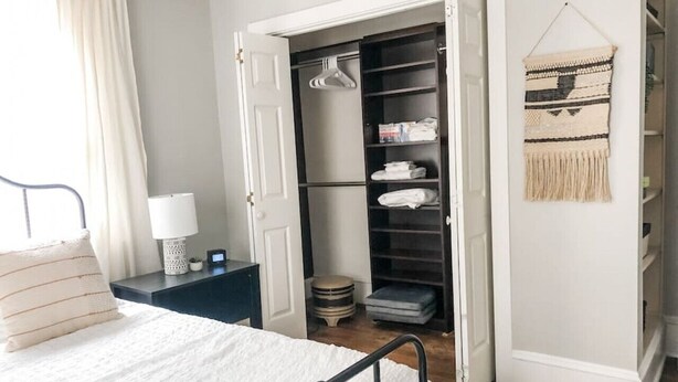 Une chambre à coucher comprenant un lit, une table de chevet, une armoire et une tapisserie murale.
