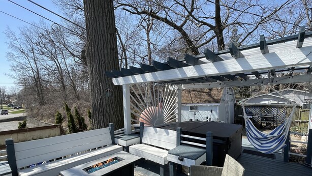 Une terrasse en bois avec un foyer, des sièges d’extérieur et une pergola.