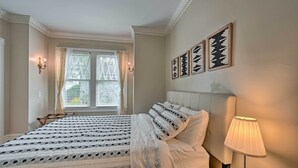 A neatly made bed with a patterned bedspread, a bedside lamp, and wall art. - Bright Greensboro Escape ~ 1 Mi to Downtown (Greensboro)
