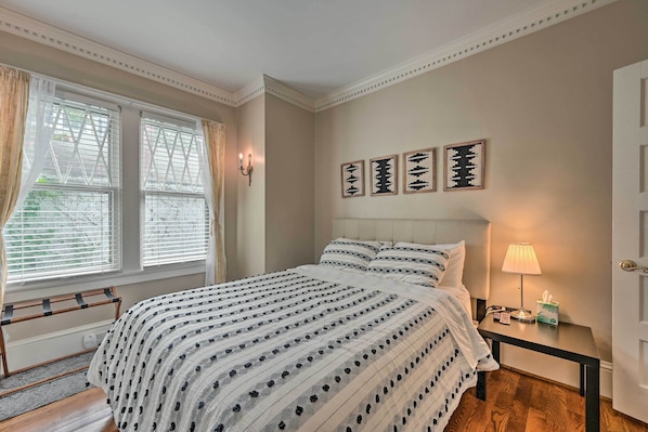 A neatly arranged bedroom with a bed, bedside table, lamp, and wall art.