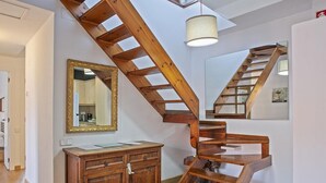 A wooden staircase with a mirror and a cabinet in a room with white walls and wooden flooring. - Duplex en Las Ramblas: tu refugio en BCN (Barcelona)