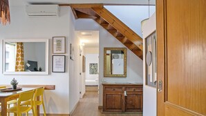 A room with a wooden ceiling, a dining area with yellow chairs, a wooden cabinet, and a mirror on the wall. - Duplex en Las Ramblas: tu refugio en BCN (Barcelona)