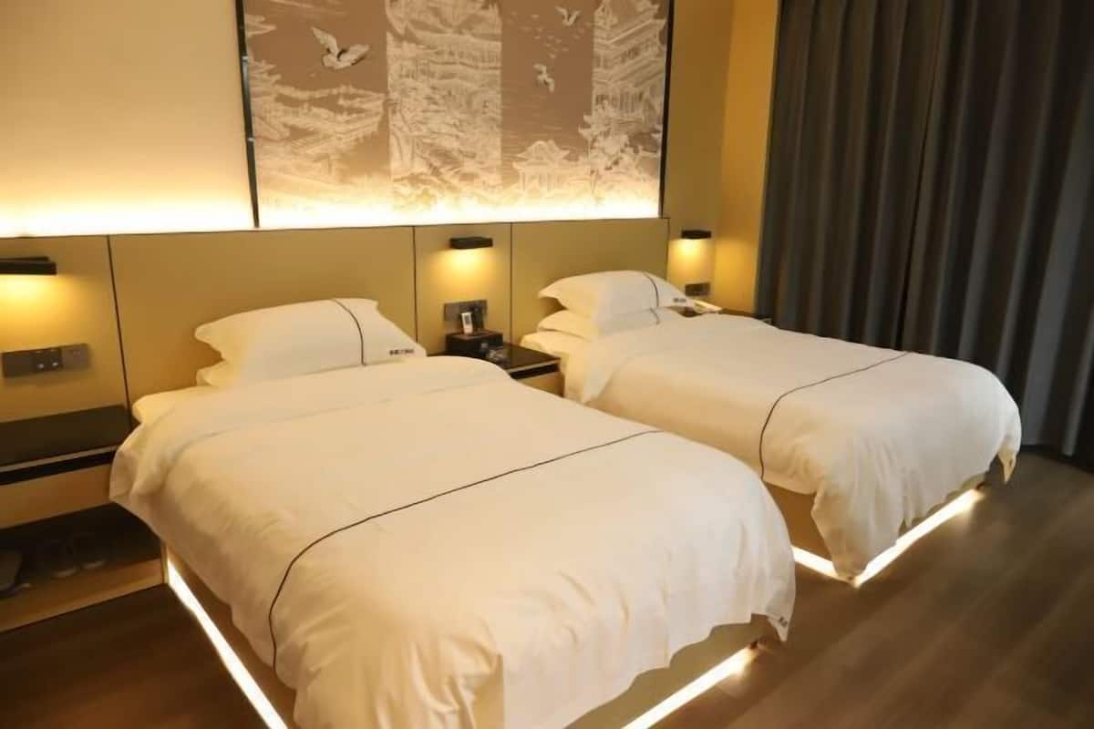 A hotel room with two beds, a large wall mural, and a curtain.