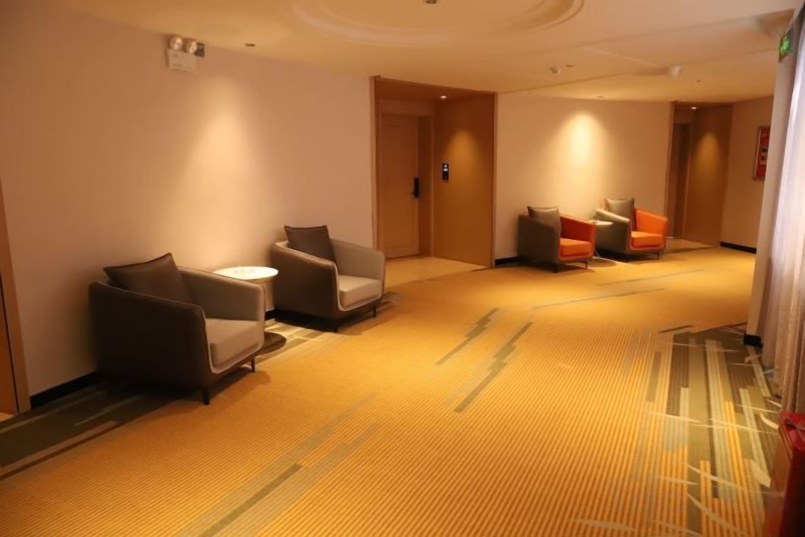 Eine Hotelhalle mit Teppichboden, einer Sitzecke mit Sesseln und einem Empfangstresen.