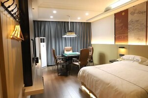 Una habitación de hotel con cama, escritorio, sillas y un equipo de aire acondicionado.