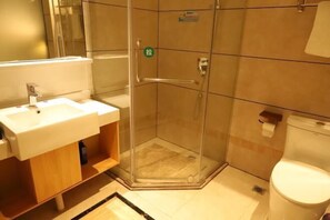 A bathroom with a glass-enclosed shower, a sink, and a toilet. - Huangsheng Hotel (Shanggao)