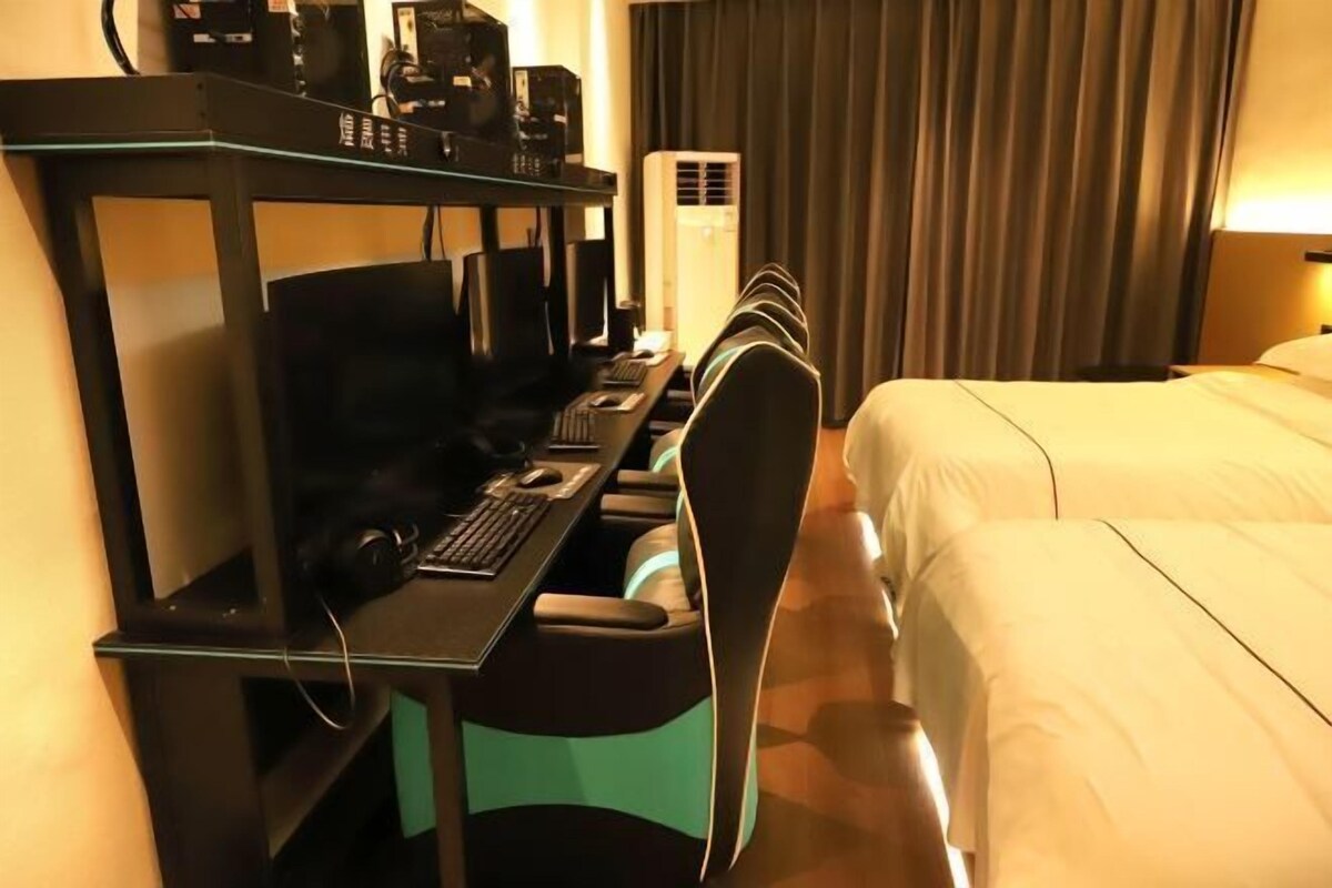 A hotel room with a desk, computer, and a bed.