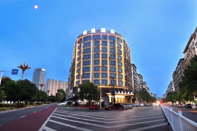 A multi-story hotel with a curved facade, located on a city street with a pedestrian crossing.