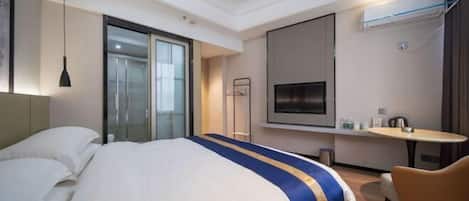 A hotel room with a large bed, a TV, a small table, and a chair.