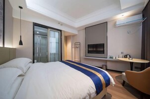 Hotellihuone, jossa on suuri sänky, televisio, pieni pöytä ja tuoli.