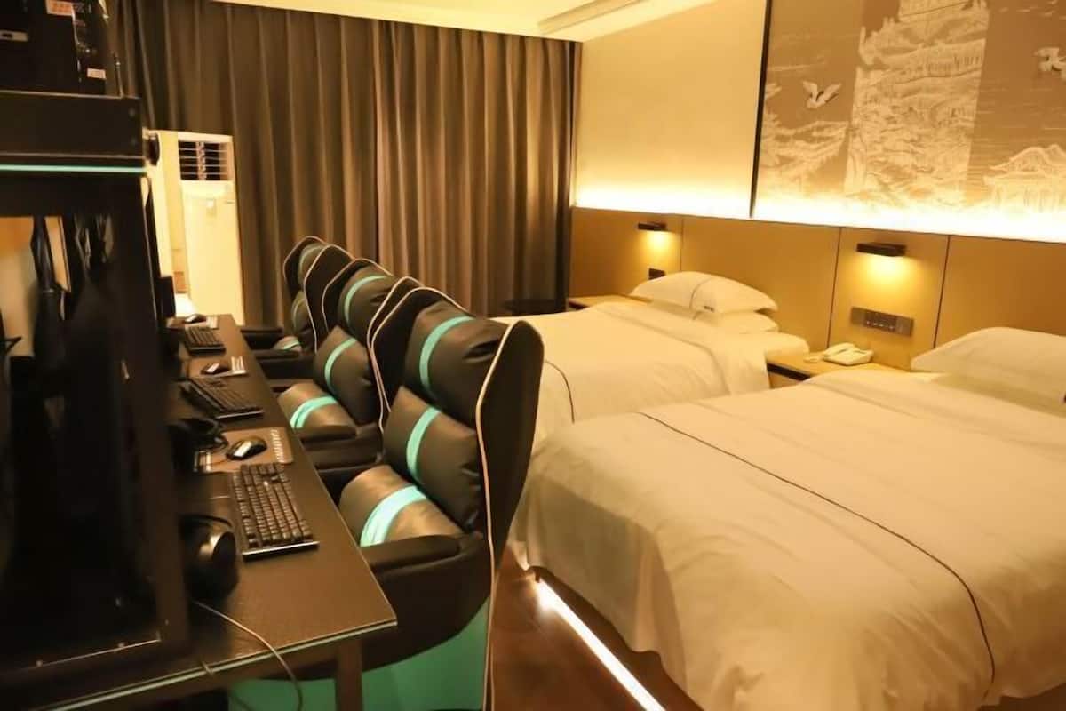 A hotel room with a desk, computer, and two beds.