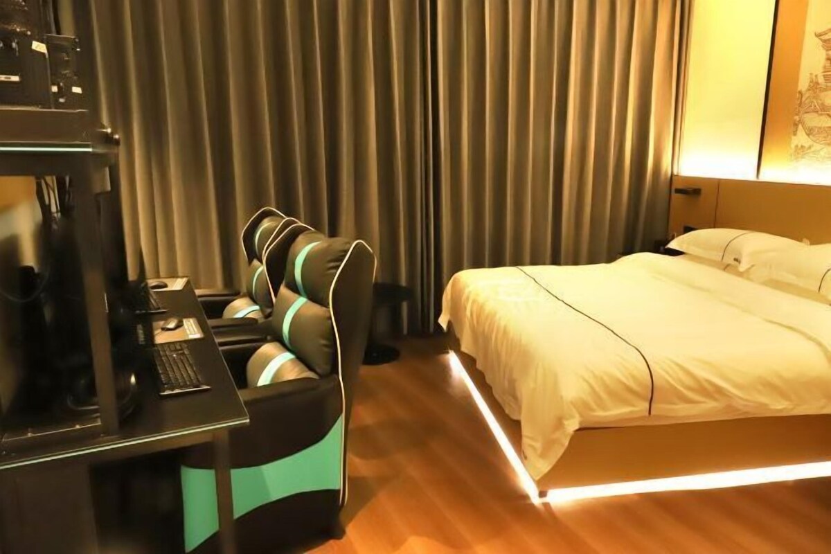 A hotel room with a bed, a desk with a computer, and a chair.