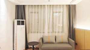 Une chambre d’hôtel moderne, équipée d’un canapé, d’une petite table ronde et d’un appareil de climatisation.