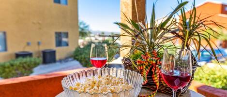 Una mesa con un tazón de palomitas, dos copas de vino tinto y una cesta decorativa con plantas.