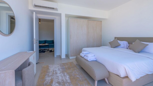 A bedroom with a bed, bedside table, bench, wardrobe, and a mirror. - Vesta - Luxury APT - 1BR - Gcribs I (El Gouna)