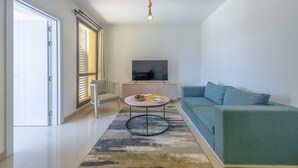 A modern living room with a sofa, a coffee table, a TV, and a sliding door. - Vesta - Luxury APT - 1BR - Gcribs I (El Gouna)