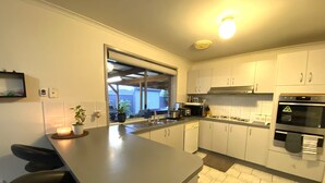 A modern kitchen with a central island, stainless steel appliances, and a view to the outside. - Entire Home In Werribee On the Best Possible Location. (Werribee)