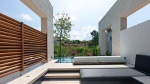 A modern outdoor relaxation area with a pool, wooden slatted wall, and a seating area with cushions. - 250m2 pool, Daily Housekeeping, Spa, 300m to beach and Shops: by etouri (Chania)