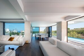 A modern living room with a sofa, a coffee table, and a dining area with chairs and a table.