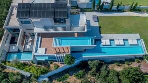 A modern house with a large swimming pool, solar panels, and a well-maintained lawn.