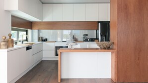 A modern kitchen with white cabinetry, a wooden island, and a large window providing natural light. - 250m2 pool, Daily Housekeeping, Spa, 300m to beach and Shops: by etouri (Chania)