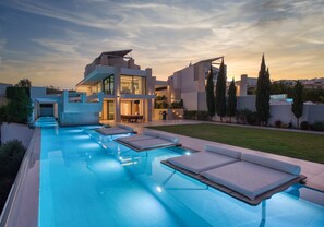 A modern pool area with lounge chairs and a building with large windows. - 250m2 pool, Daily Housekeeping, Spa, 300m to beach and Shops: by etouri (Chania)