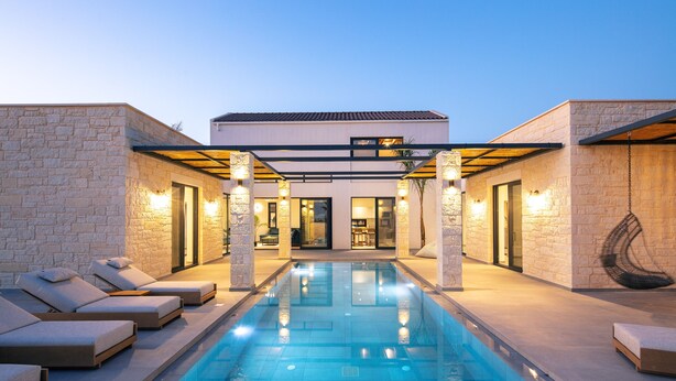 A modern pool area with lounge chairs and a clear pool, surrounded by stone walls and a building with a flat roof. - Ikritis Villa Ι - 1,2Km to beach & sea views! (Chania)
