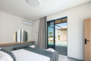 Ein modernes Hotelzimmer mit Bett, Nachttisch, Spiegel und einer Glastür, die zu einem Poolbereich führt.