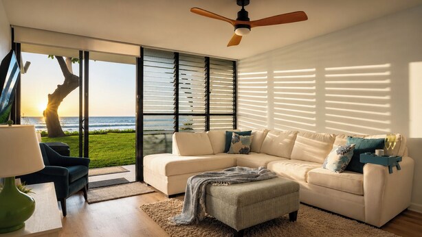 A modern living room with a large window, a ceiling fan, and a view of the ocean.