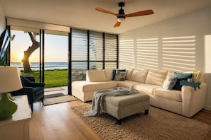 Een moderne woonkamer met een groot raam, een plafondventilator en uitzicht op de oceaan.