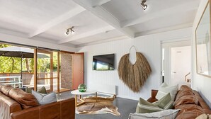 A spacious living room with leather sofas, a round coffee table, and a large TV mounted on the wall. - Rye Beach Abode - STAY 3 PAY 2 SPECIAL OFFER! Expires 1st September 2025 (Rye)