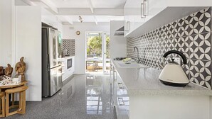 A modern kitchen with a sleek countertop, a kettle, and patterned backsplash. - Rye Beach Abode - STAY 3 PAY 2 SPECIAL OFFER! Expires 1st September 2025 (Rye)