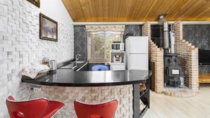 A kitchen with a black countertop, white brick backsplash, and a brick stove.