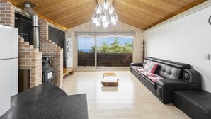 A spacious living area with a fireplace, a black leather sofa, and a wooden ceiling.