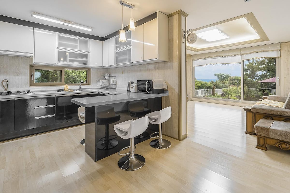 Una cocina moderna con una isla central, taburetes de bar y vistas al exterior.