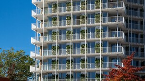 Un immeuble à plusieurs étages doté de balcons, chacun orné de plantes.