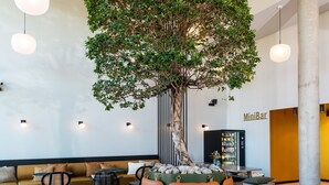 Un espace de détente moderne avec un grand arbre, des sièges confortables et un mini-bar.