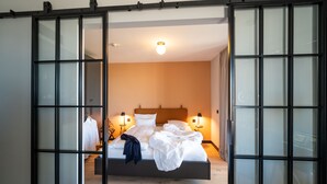 Une chambre à coucher avec un lit, des lampes de chevet et une vue sur l’extérieur, accessible par une porte coulissante.