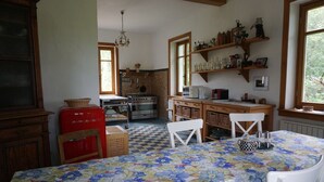 A kitchen with a checkered floor, a red refrigerator, a stove, and a dining table with a floral tablecloth. - Romantisches Ferienhaus Mitten in der Natur (Wiesbaden)
