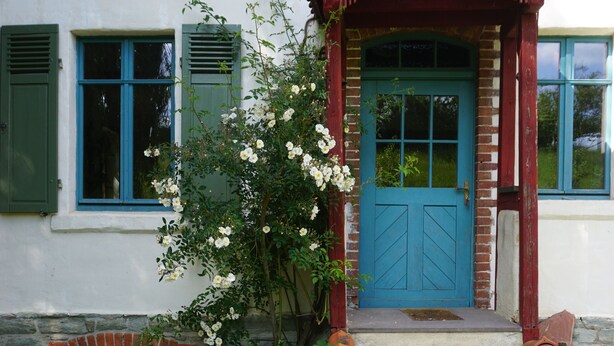 A house with a blue door, green shutters, and a brick fireplace. - Romantisches Ferienhaus Mitten in der Natur (Wiesbaden)