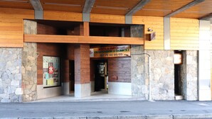 Un bâtiment à la façade en pierre et dont l’étage supérieur est en bois. On y voit une enseigne indiquant un restaurant de pizzas et un magasin d’articles de sport.