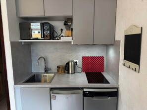 Une cuisine compacte équipée d’un lave-vaisselle, d’une bouilloire et d’un four à micro-ondes posés sur le plan de travail.