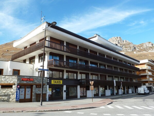 A multi-story building with a 'TAXIS' sign, a stone facade, and a mountain backdrop.
