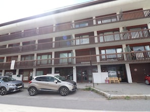 A multi-story building with balconies, a parking area, and a storefront. - Bright 2-room apartment in Tignes, near slopes and shops (Tignes)