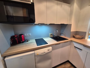 A compact kitchen with a dishwasher, a sink, a microwave, and a red coffee maker. - Bright 2-room apartment in Tignes, near slopes and shops (Tignes)