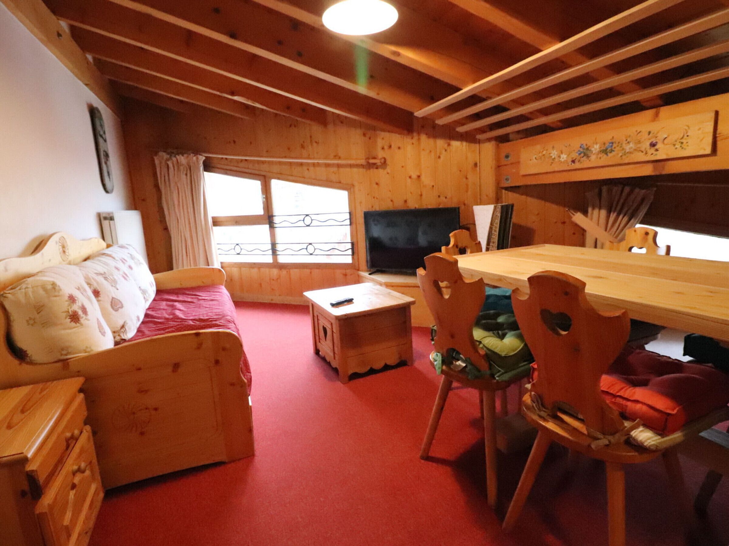 A cozy wooden room with a bed, a desk, and a TV.