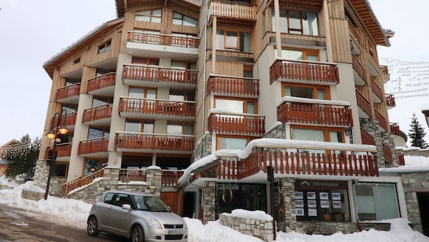 A multi-story hotel with wooden balconies, stone facade, and a car parked in front. - Comfortable Apartment in the Heart of Tignes le Lac, Ideal for 6 People (Tignes)